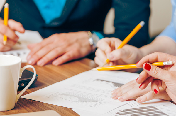 Department policies Hands holding pencils over a coffee meeting.